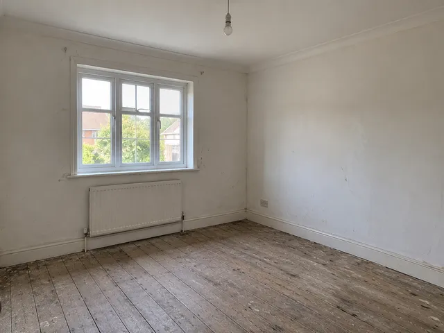 The bedroom before work began — bare floorboards, patchy plaster and no decoration.